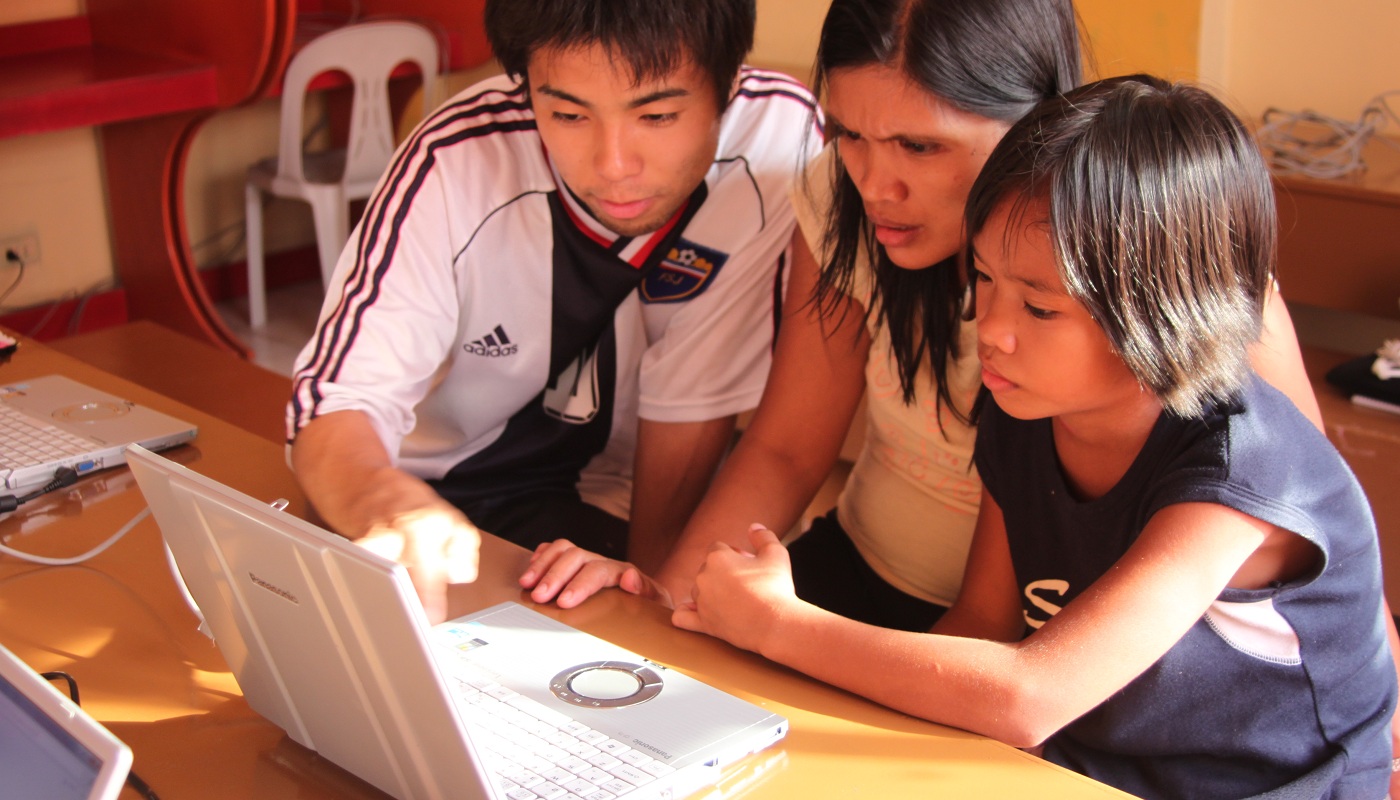 マニラのスラム地域に住む自営業の親子に収支計算方法を教えている様子