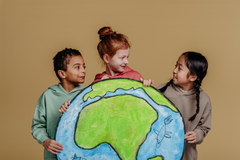 Portrait of three children with model of Earth, studio shoot. Concept of diversity in friendship.