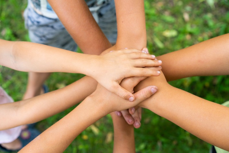 children holding hands standing on the green grass, the concept of friendship and a group of young people working in a team
