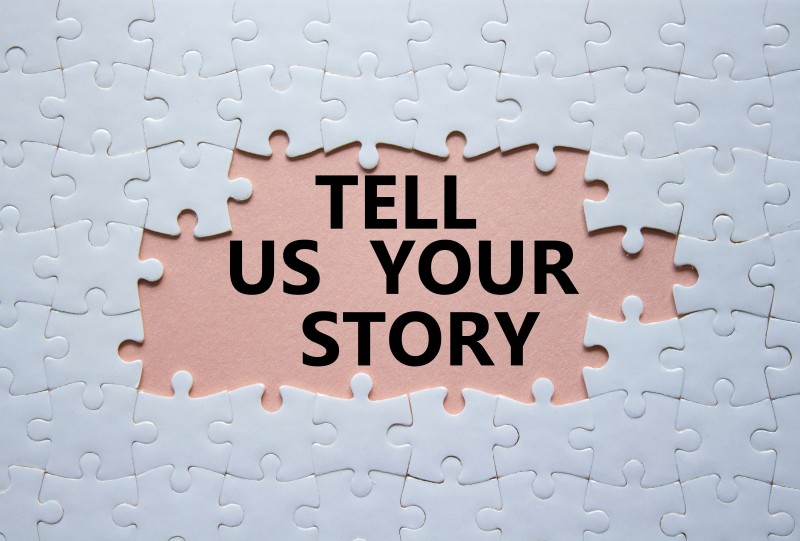 Tell us your story symbol. Concept words Tell us your story on white puzzle. Beautiful pink background. Business and Tell us your story concept. Copy space.